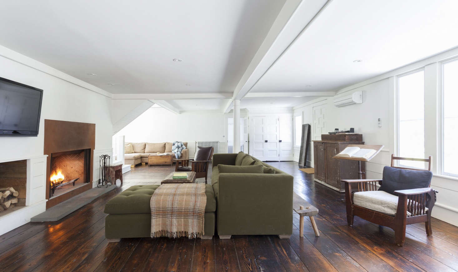 The open-plan living room/family room/dining room has its own steel-front fireplace and original wide-plank floors. The wainscoting and ceiling coffers were built from pine trees felled and milled on the property. The living room is painted in Benjamin Moore