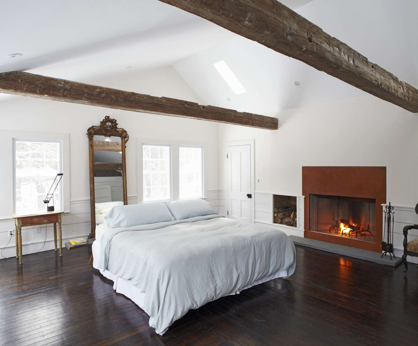 In the master suite–one of five bedrooms–the bed is floated in front of an antique mirror and alongside a wood-burning fireplace.