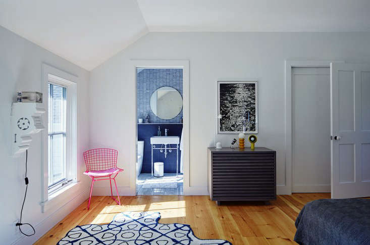 Another pink Bertoia chair appears in the master bedroom. A Leslie Parke painting of water hangs over a collection of vintage lights. The rug is Gandia Blascoe&#8