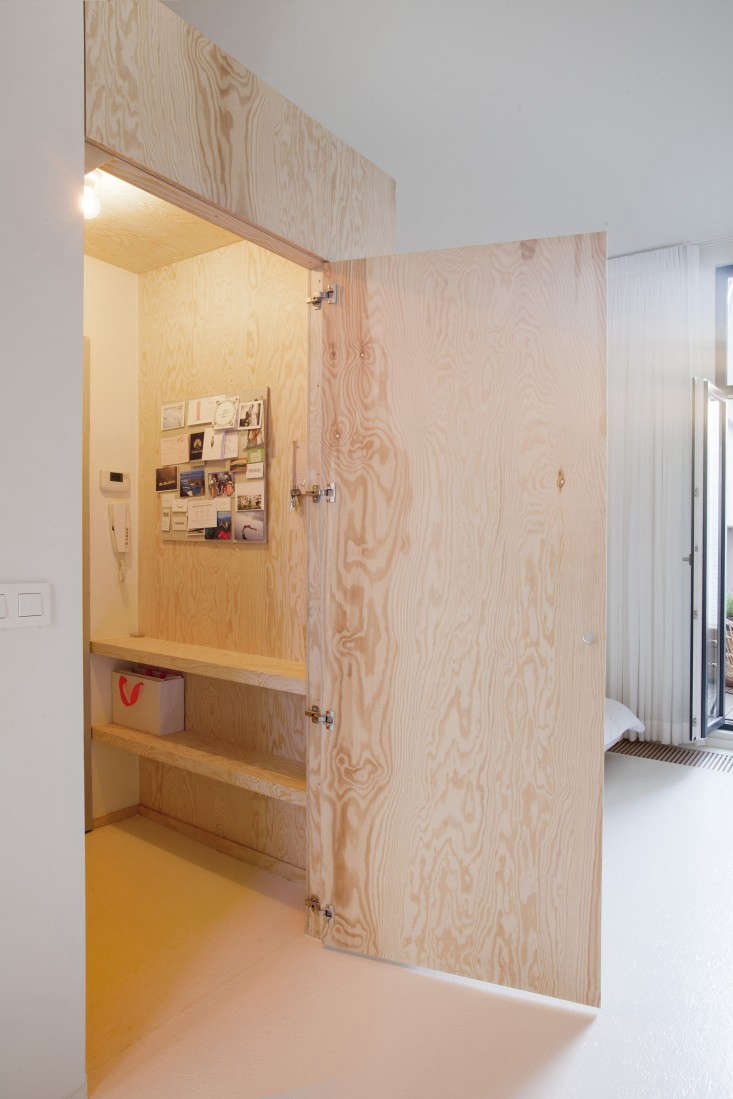 a plywood door conceals a small room with shelves and a wc in the perfect  28