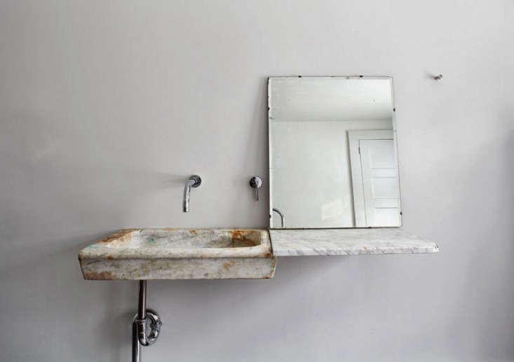 an \18th century italian marble sink connects to a floating slab of carrara for 18