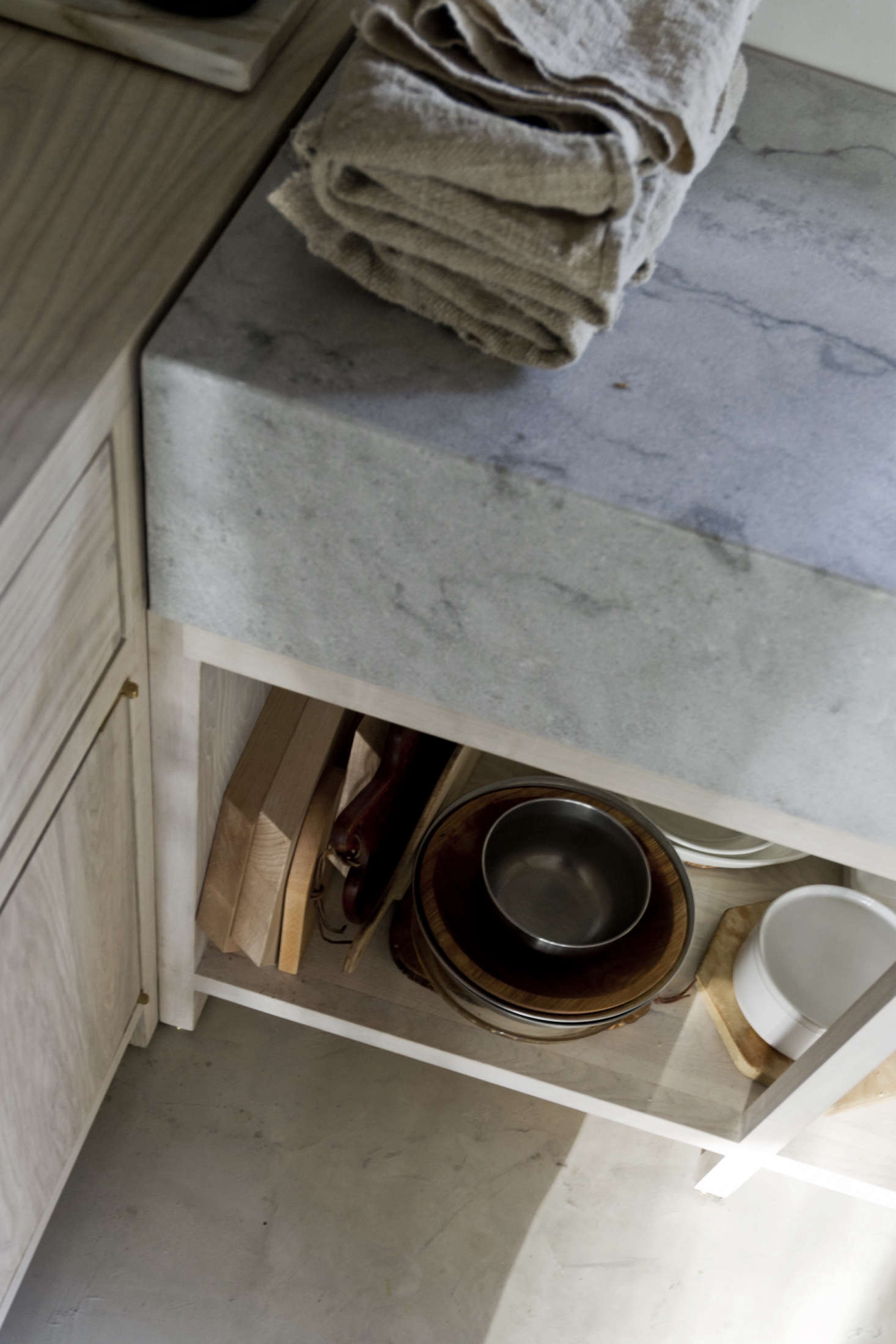 Cutting boards and pots and pans—all wood, metal, and white enamelware—are stored under the counter. David