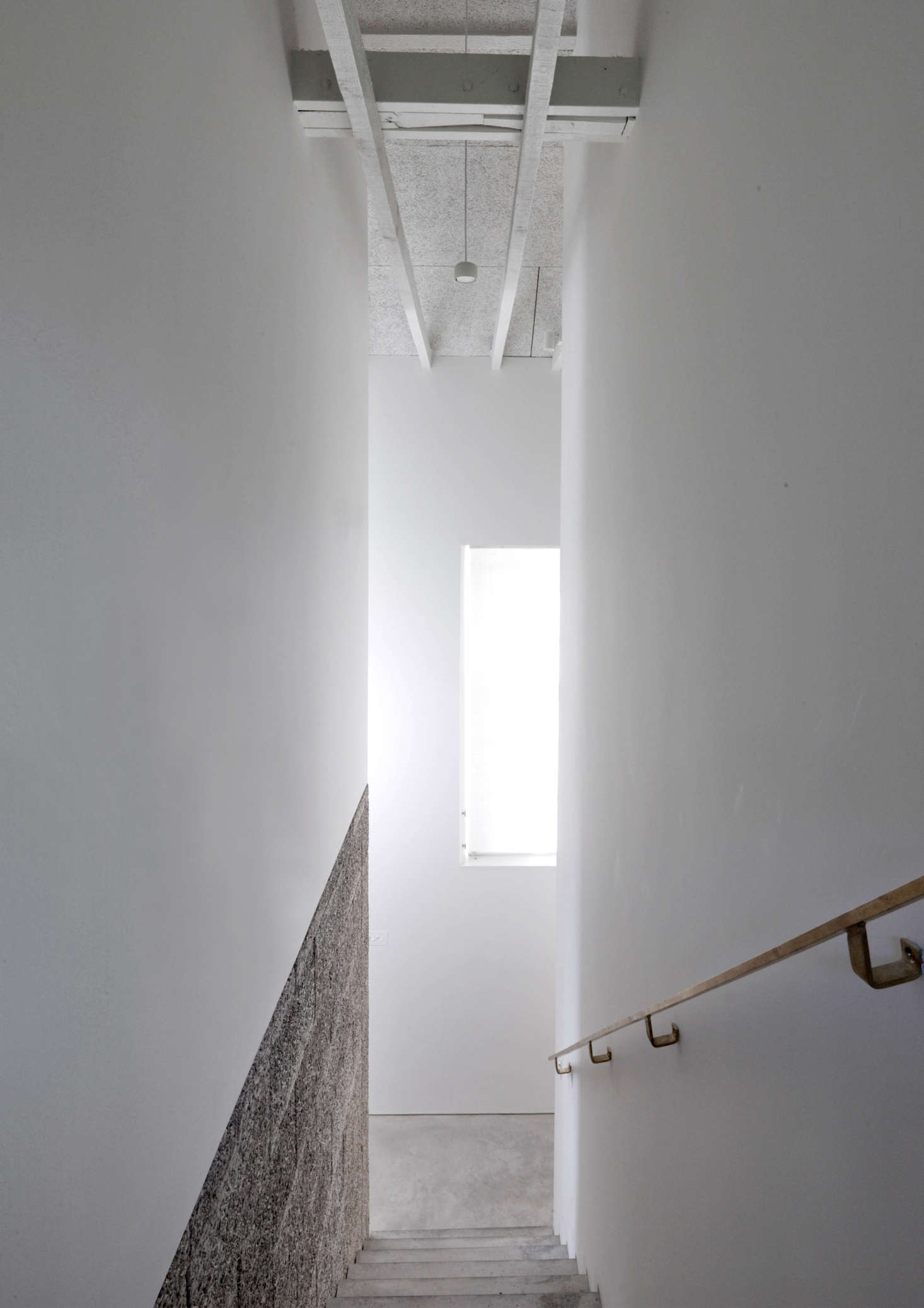 For a lighter effect, the Durisol is paired with drywall. The elegant handrail is fabricated entirely of brass.