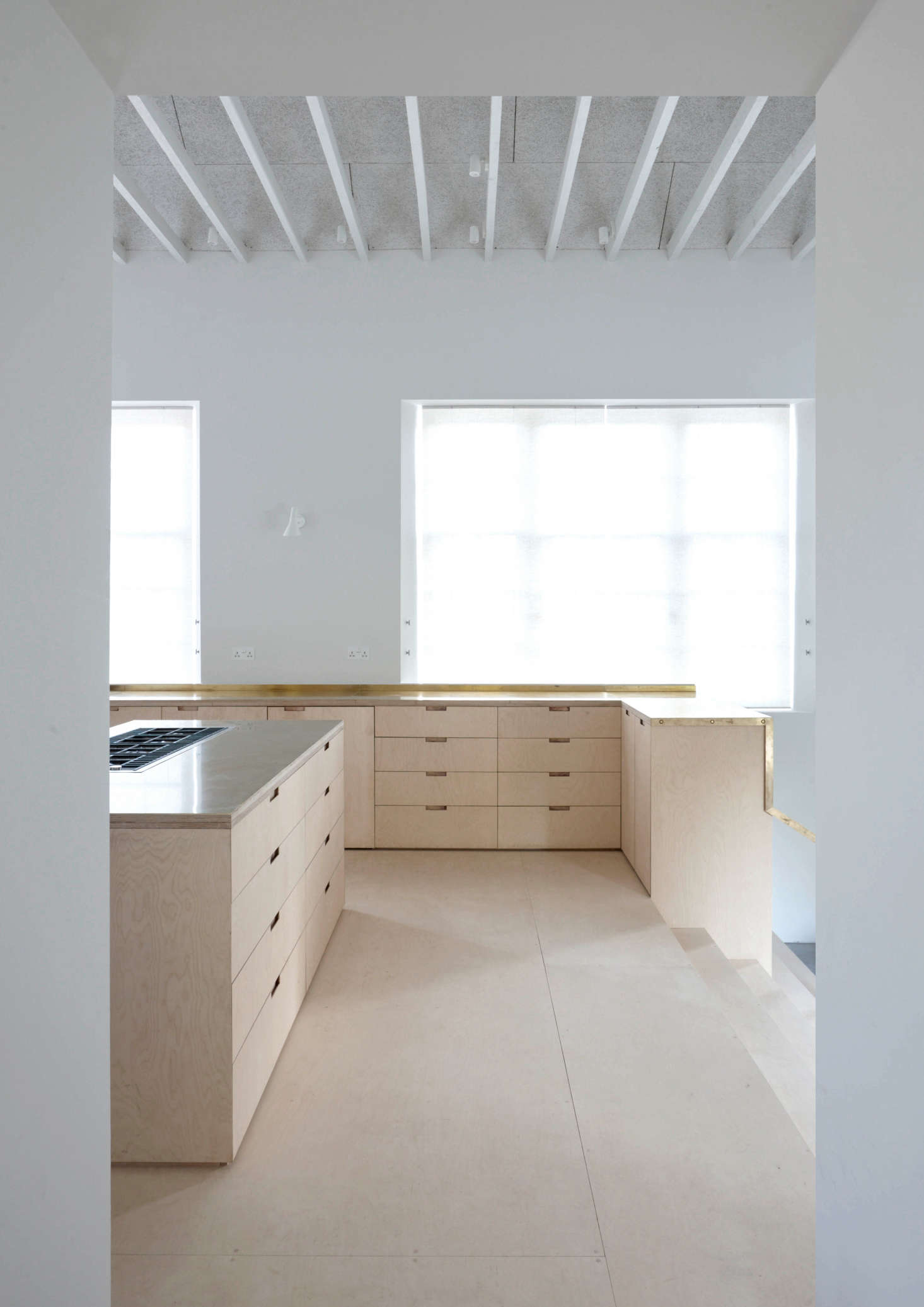 Large new windows flood the space with light. In addition to being lit from the rafters, the room is lined with sconces, including the AJ Wall Sconce by Arne Jacobsen.