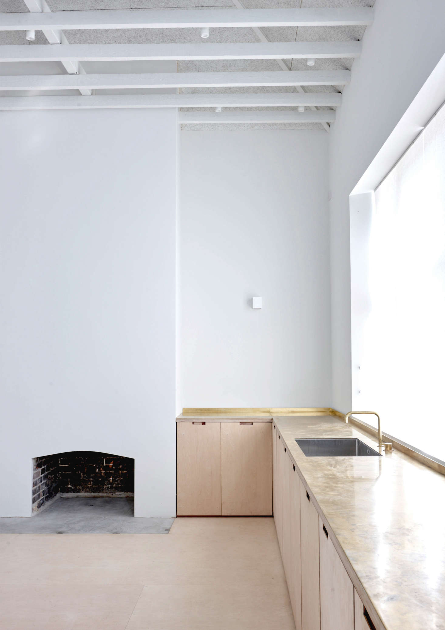 Brass countertops and a Vola faucet add an element of luxury to the space. The original hearth was preserved in a new guise.