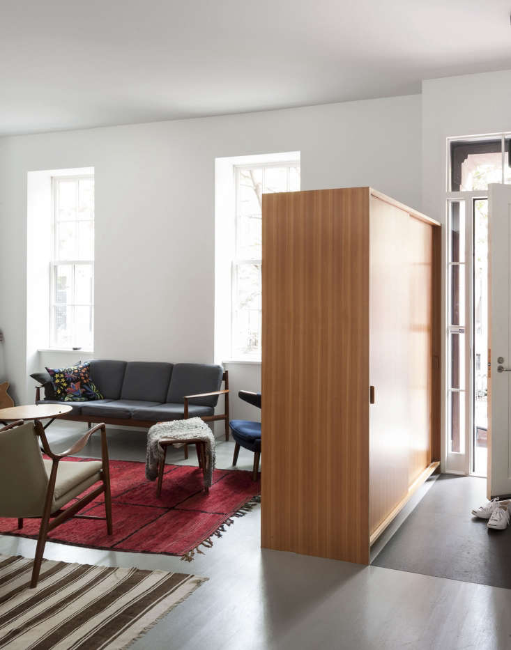 a freestanding cabinet serves as coat closet and room divider, creating a separ 21