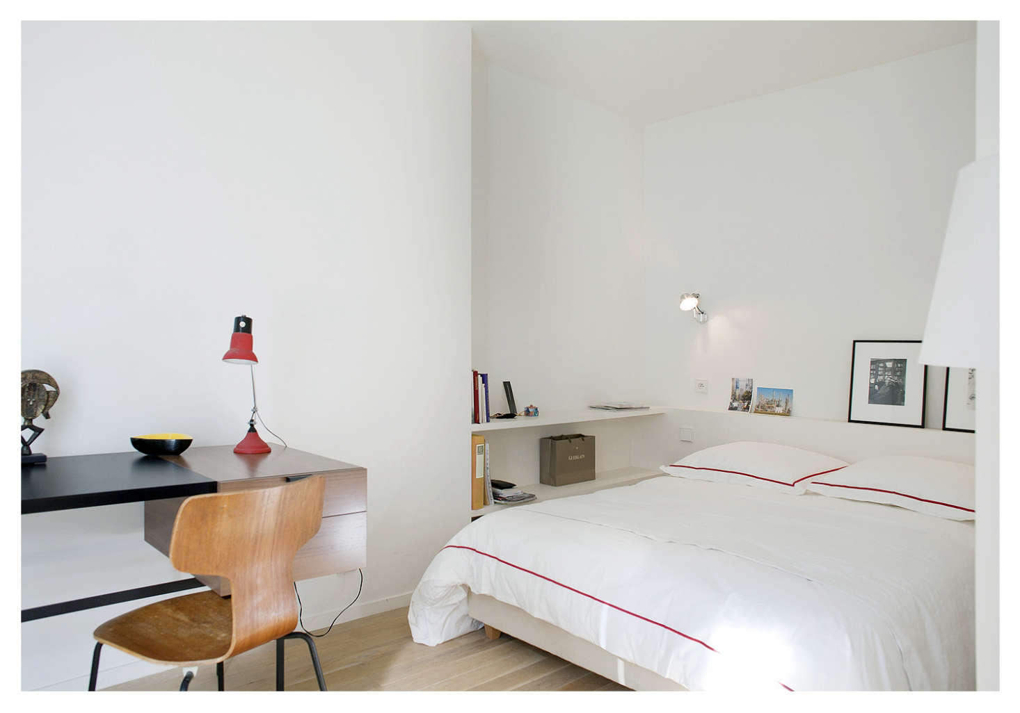 A ledge and bedside shelving take the place of tables in a small Paris bedroom designed by architect Philippe Harden. The midcentury desk is by Pierre Paulin.