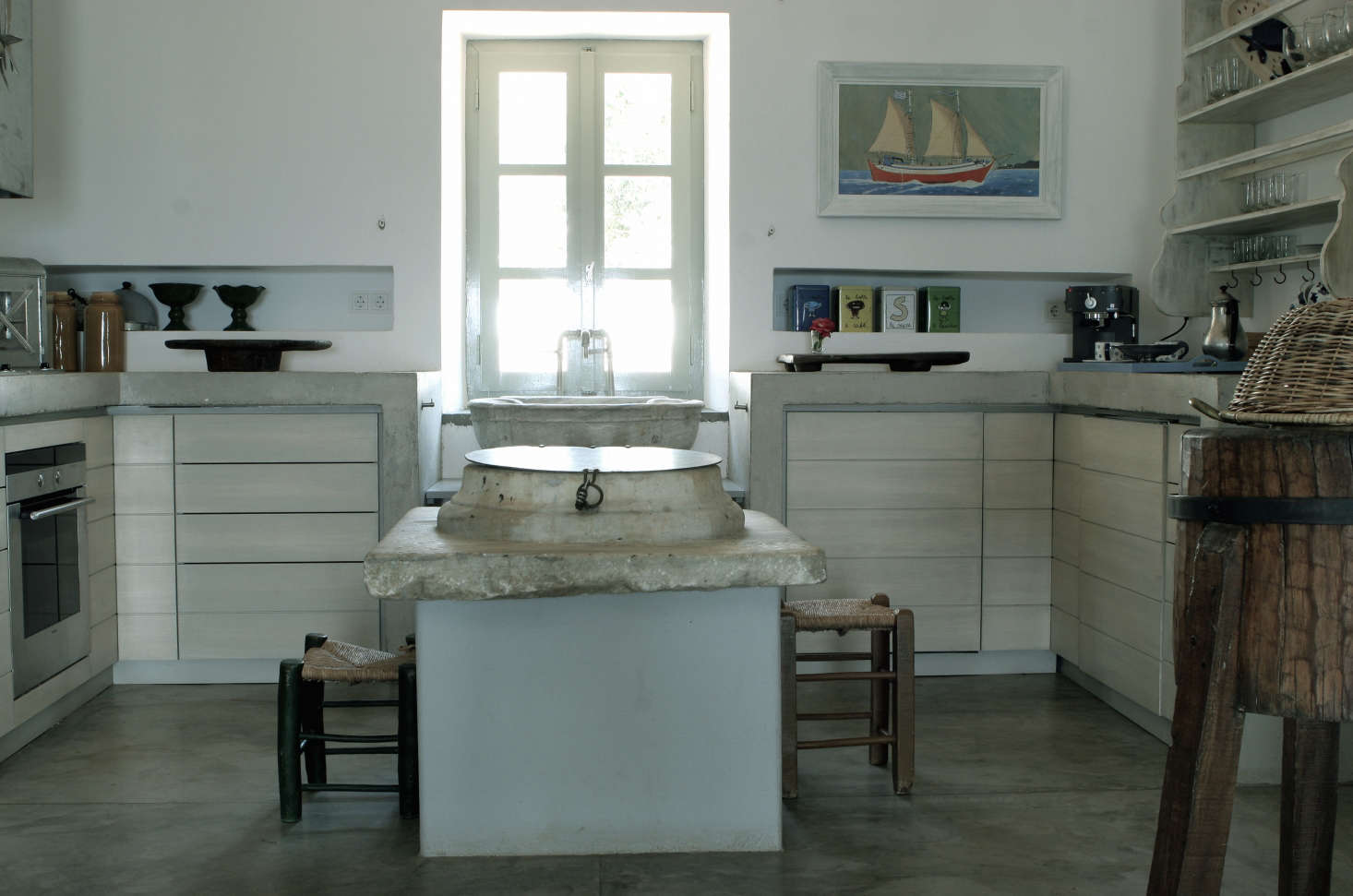 Also from the family collections, a marble piece from an old well serves as the top of the pale blue concrete kitchen island. Photograph by Costas Picadas, courtesy of Zoumboulakis Architects.