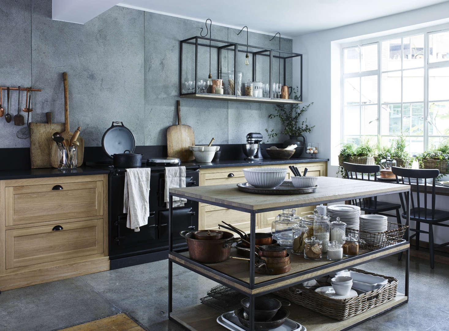 In the center of this kitchen, the stylists at the showroom have stacked two industrial-look coffee tables to create an open kitchen island and worktop. (Evidently, they’ve fashioned an extra surface at the base of the structure to create a third wooden shelf.)