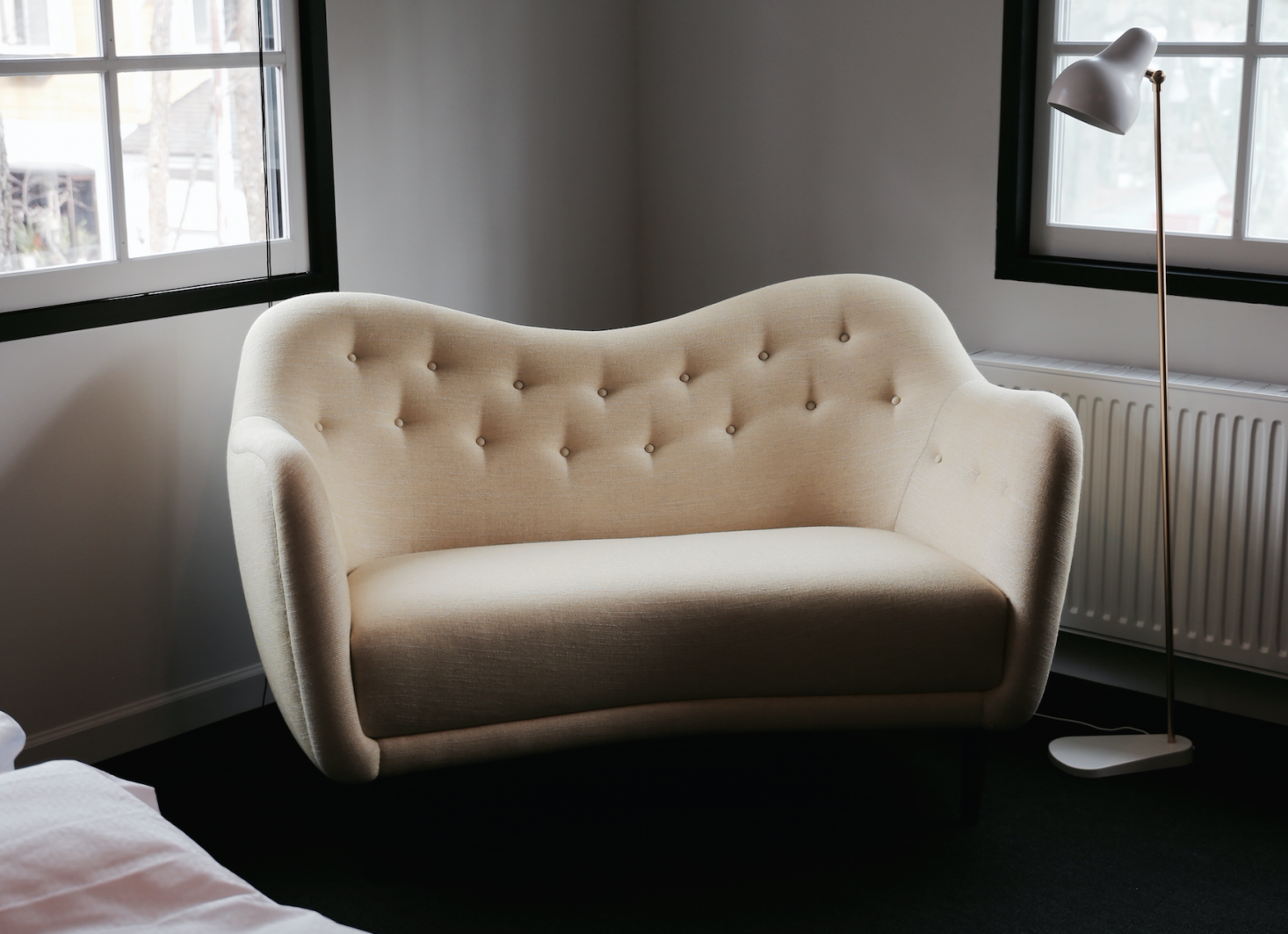 A curvaceous 46 Sofa, illuminated by a newly reissued VL38 Radiohus Floor Lamp (currently on sale starting from $649.40 from YLighting).