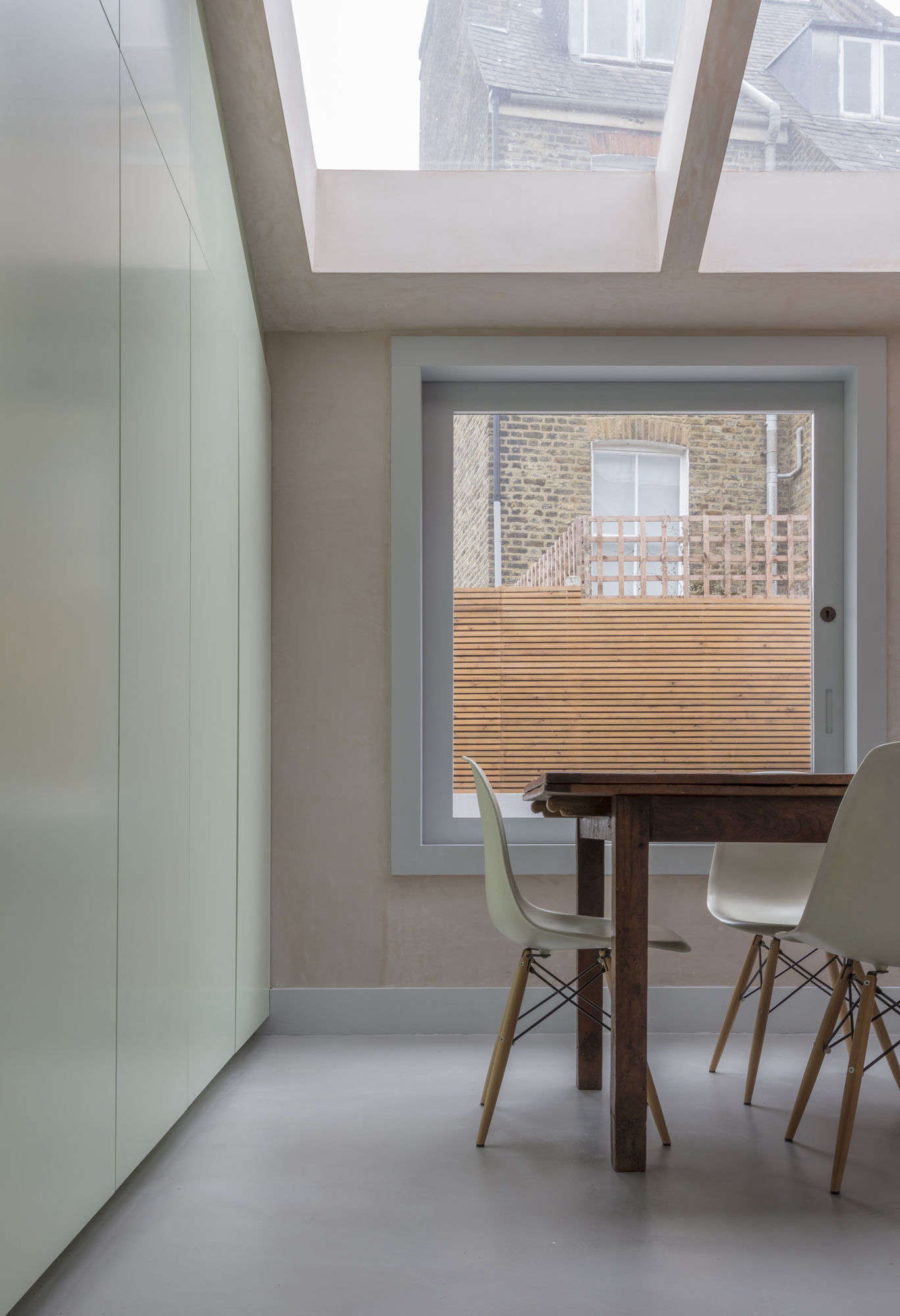 To keep the room clutter free, the architects included a long wall of seamless built-in storage in pale green spray-painted MDF. 