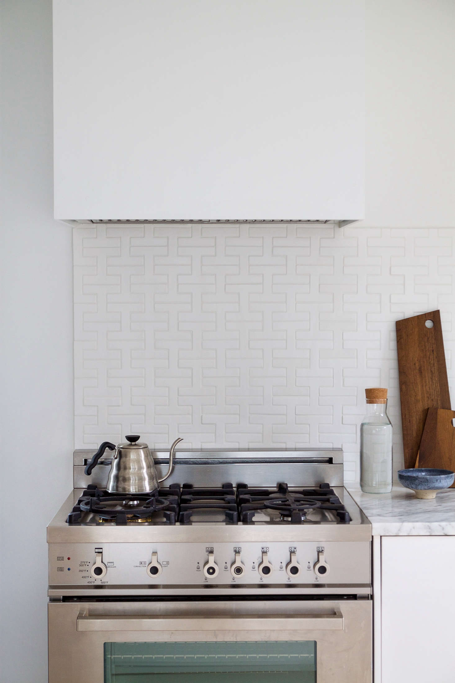 Splurges included a Bertazzoni Pro-Series 30-Inch Gas Range; $3,350. Disguising another Bertazzoni hood, the contractor built a custom box of simple plywood. Painted the same white as the walls, it blends seamlessly into the space.