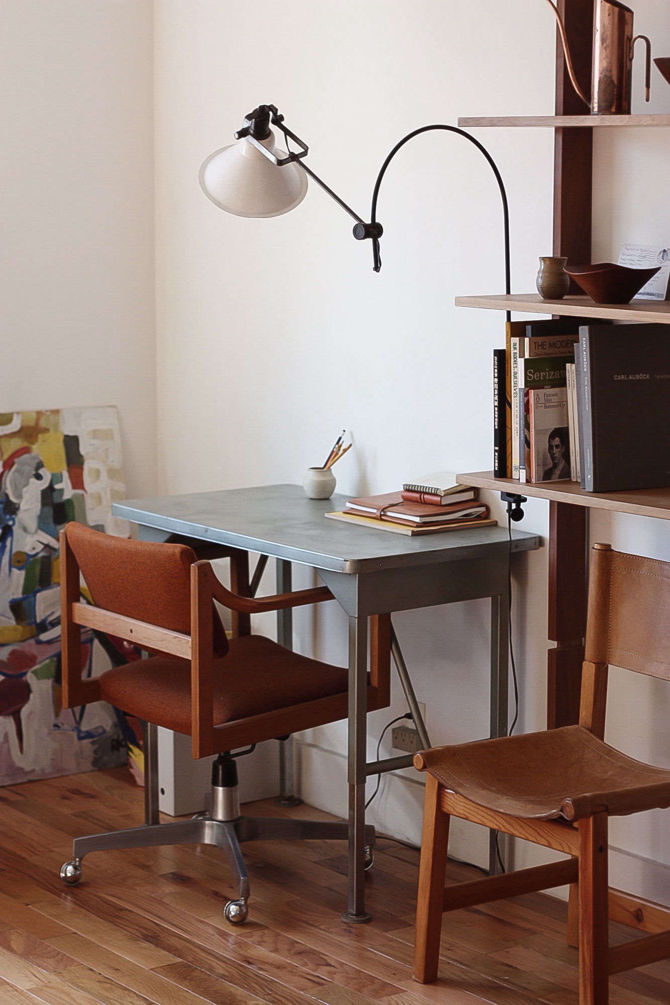 In the office, an industrial desk and chair are illuminated by a flea-market find.