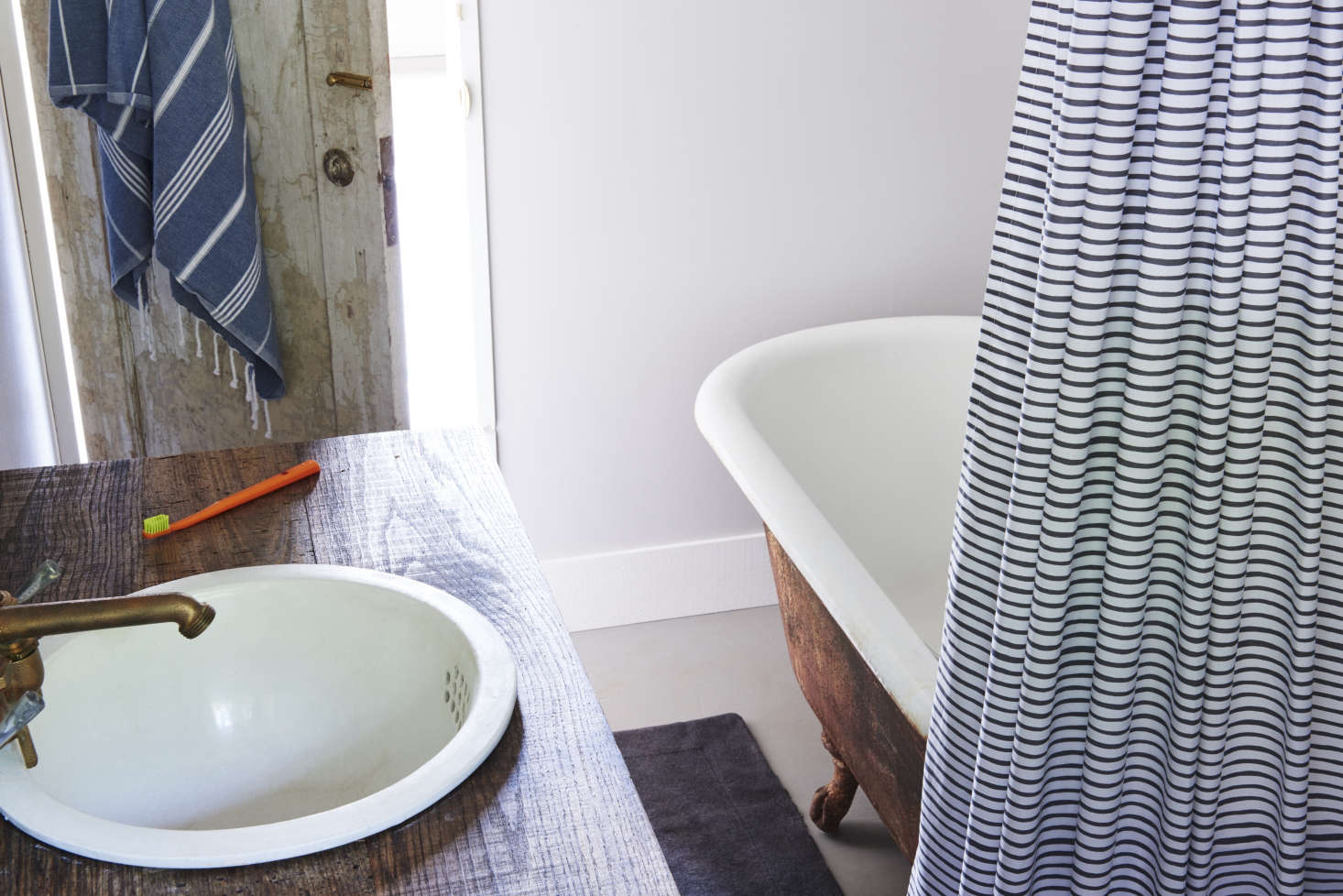 The small bath is well-appointed for country life, with an antique cast-iron tub and vintage porcelain sink.