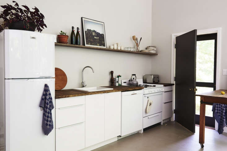 inside: a small all white kitchen, complete with butcher block countertops, for 18