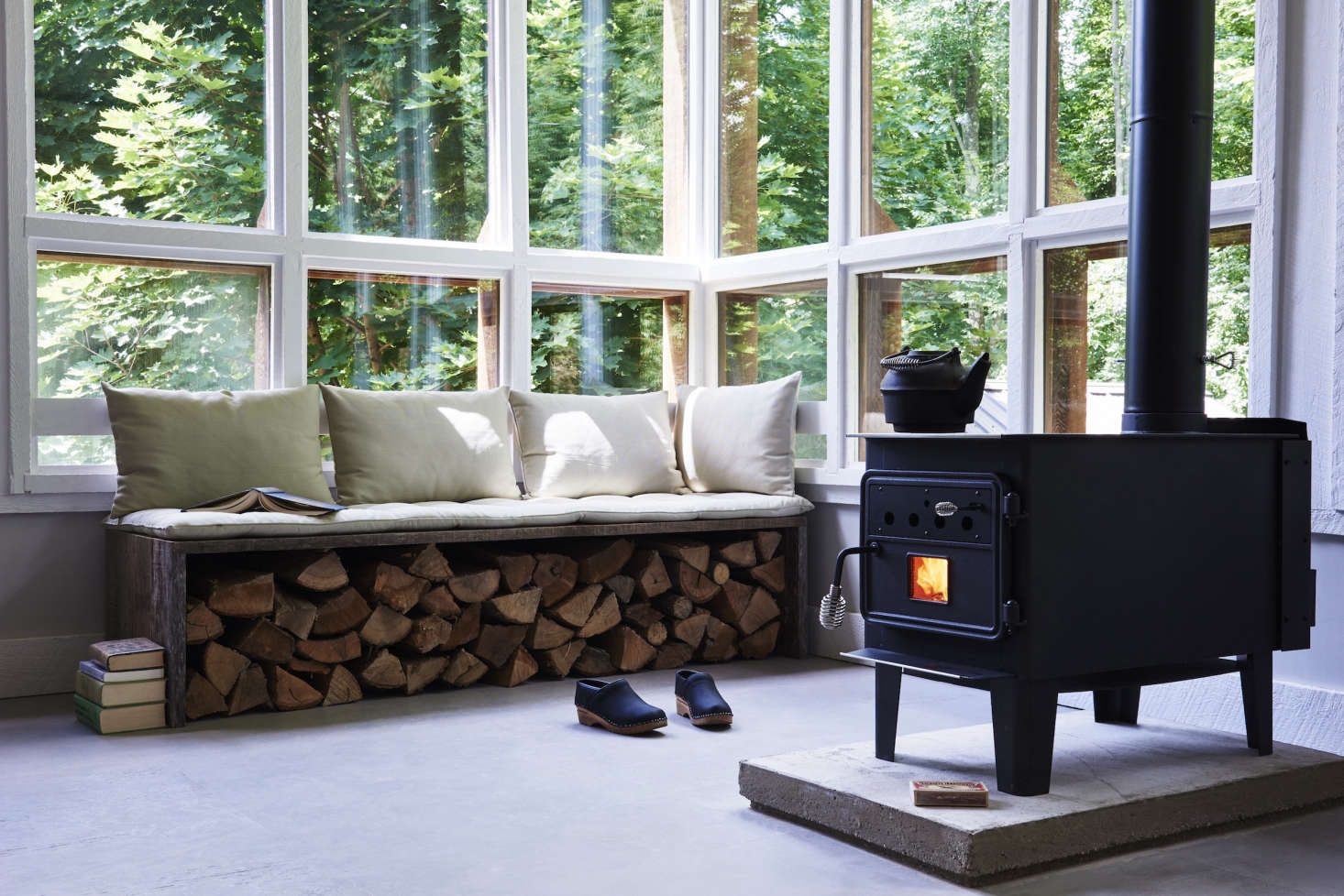 Near the Vogelzang Durango woodstove is an inventive storage solution: stacked logs tucked beneath a bench.