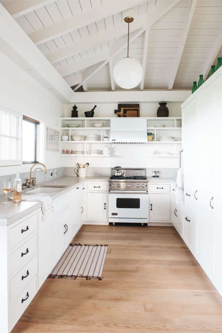 the kitchen features white painted cabinetry and a sliding window above the sin 22