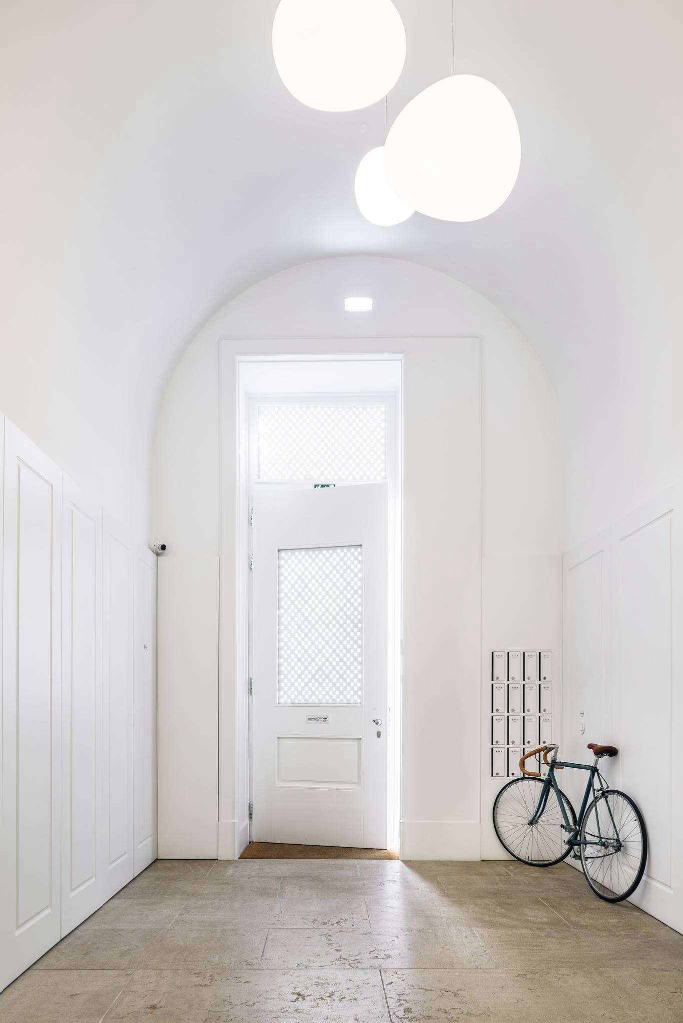 The all-white entryway, with a bicycle available for rent. The original detailing and soaring ceilings of the factory were preserved throughout.
