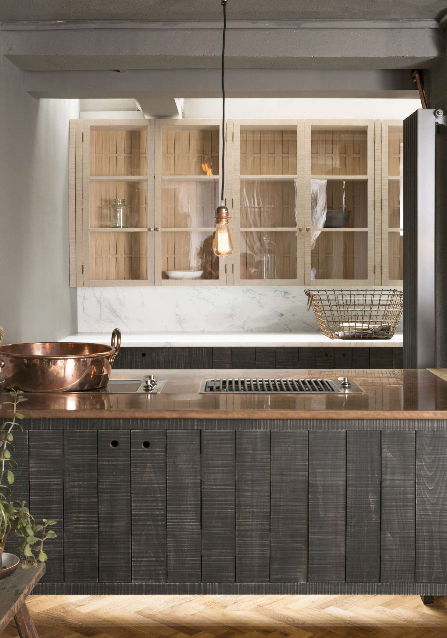 The island is topped with mixed materials: oak at the prep end and patinated copper around the Smeg Domino cooktop and grill.