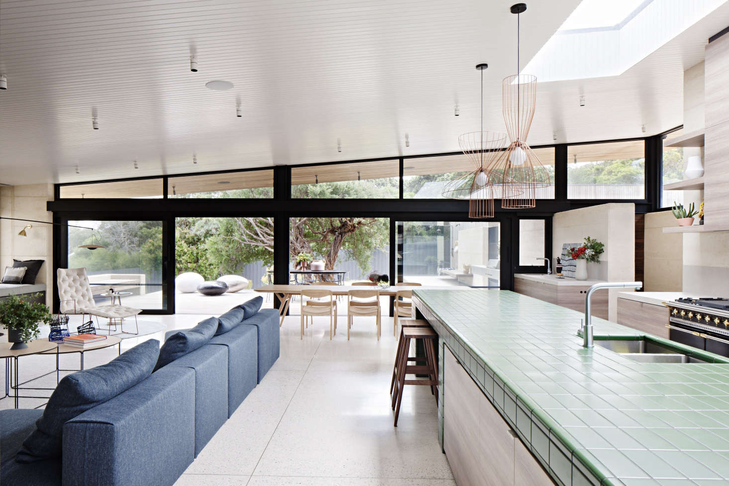 Designed as a gathering place for a multigenerational family and their many guests, the house revolves around a central living/dining/cooking area with a clean-lined, organic-modern look.