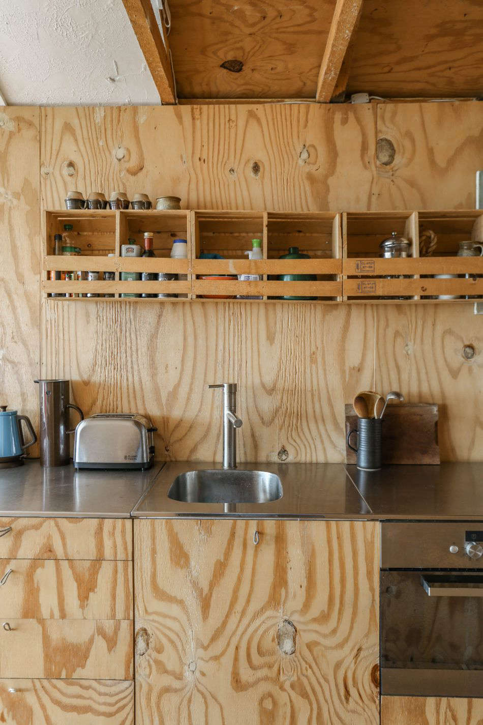 The plywood front Ikea kitchen features loops of rope from a sailing shop as hardware. Photograph by Marcia Mihotich from Two London Creatives Shore Up a Tiny Beach House, Ikea Hack Kitchen Included.