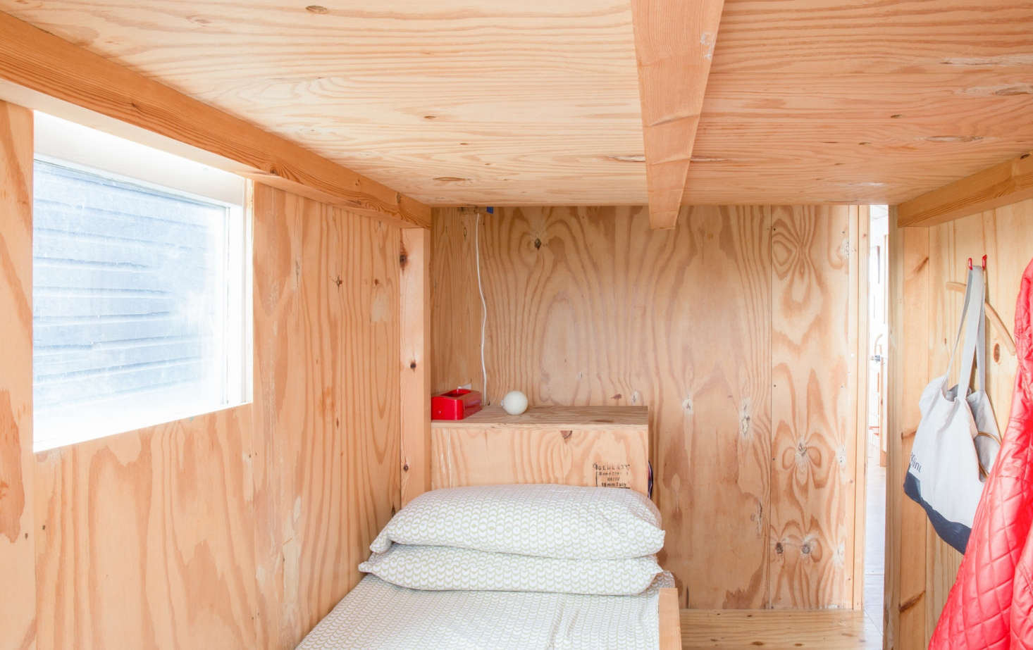 The bedroom has a twin bed and a sleeping loft big enough for two. In addition to wall hooks, there are storage bins incorporated into the steps to the loft.