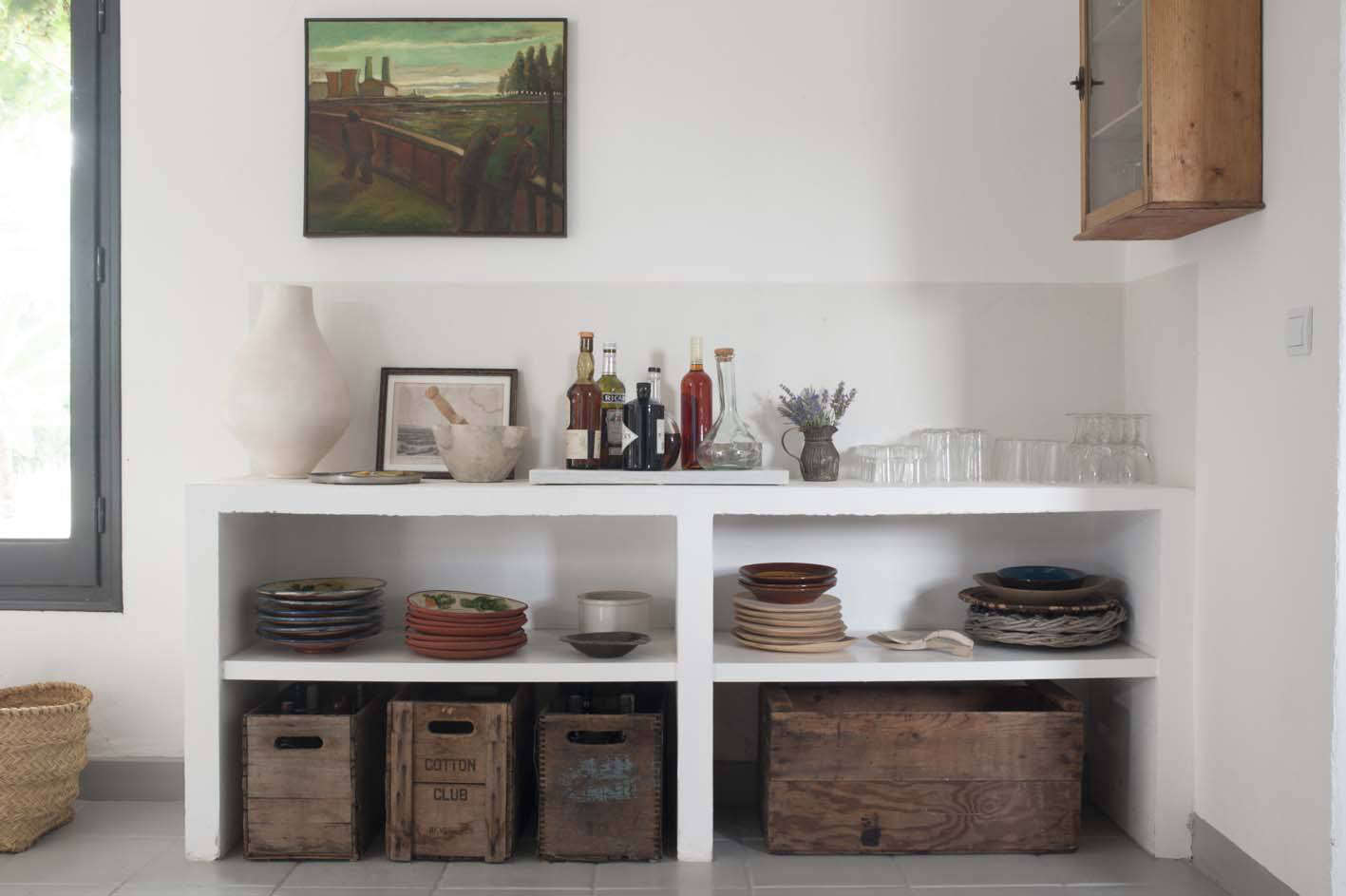 a plaster open sideboard holds dishes; the wooden crates store wine and extra g 19