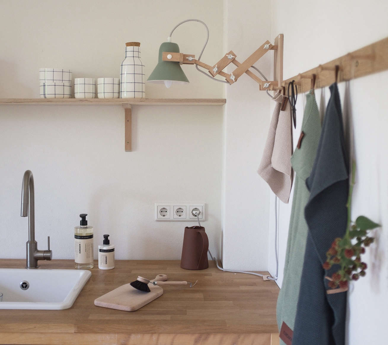 Swantje continually changes up the look of her kitchen by swapping in different dish towels. The wooden accordion wall light is the Pixoss XL by Dutch designer Studio M.oss.