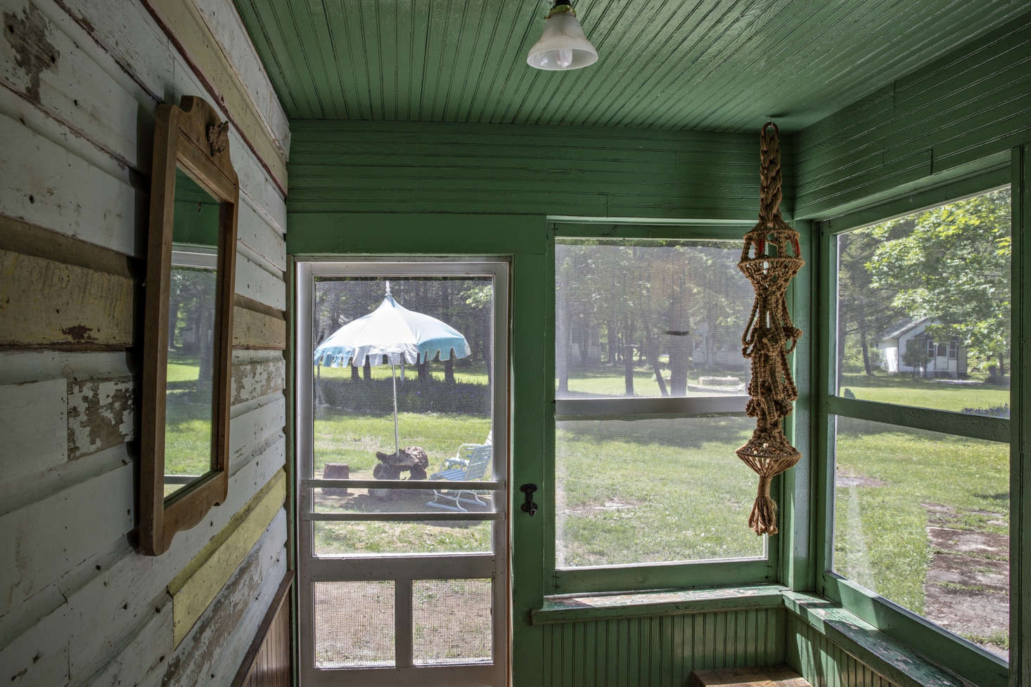 A screened porch with interior cladding, painted green.