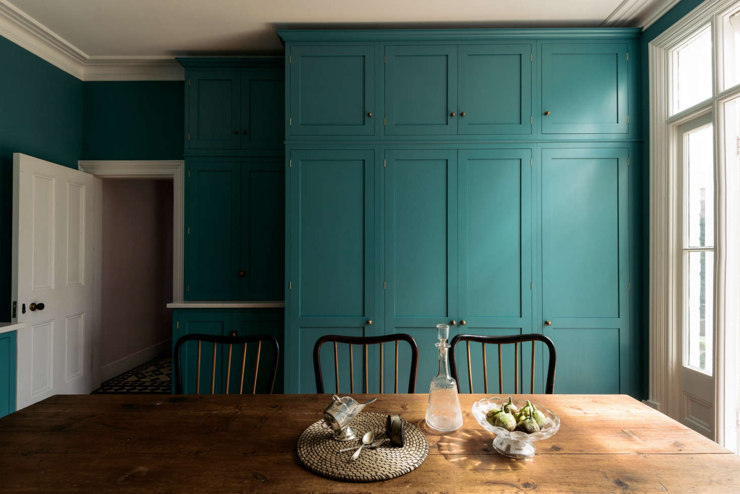 Fitted cabinets on the back wall contain a full-size refrigerator and freezer on either side of a double-door larder.