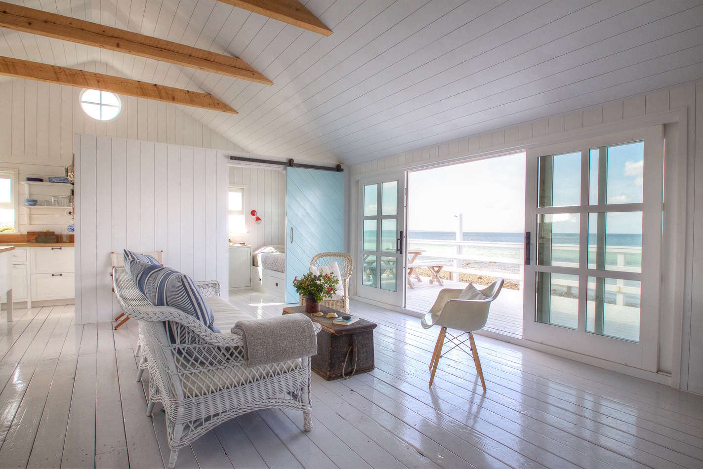 The main living area has sliding doors that open to a deck overlooking a stretch of sandy beach.