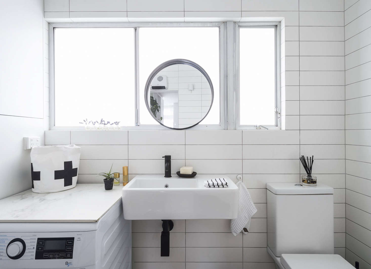 Spath removed a half-wall beside the toilet to open up the small bath. In lieu of a vanity, she sourced a wall-mounted sink (for something similar, see Easy Pieces: Wall-Mounted Modern Square Bath Sinks), and topped the washing machine with a piece of marble from an old table that the client owned. Now it