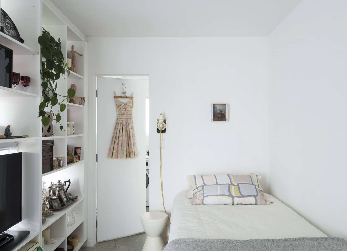 In the bedroom, a wall-mounted sconce found online provides reading light; a Prince Aha Stool by Kartell acts as a movable bedside table.