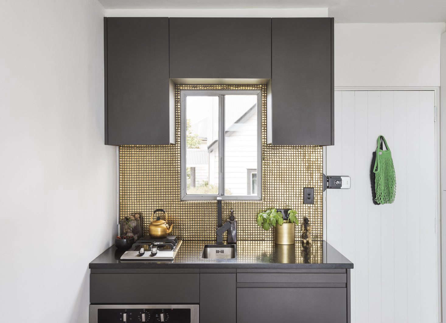 The new kitchenette is tiny but bold: Spath painted the cabinetry in Nero by Resene Paints; the tiles in the backsplash are from Tile Space in Auckland. In the spirit of tiny but efficient kitchens, Spath chose a small-space sink and range (see Easy Pieces: Best Appliances for Small Kitchens).