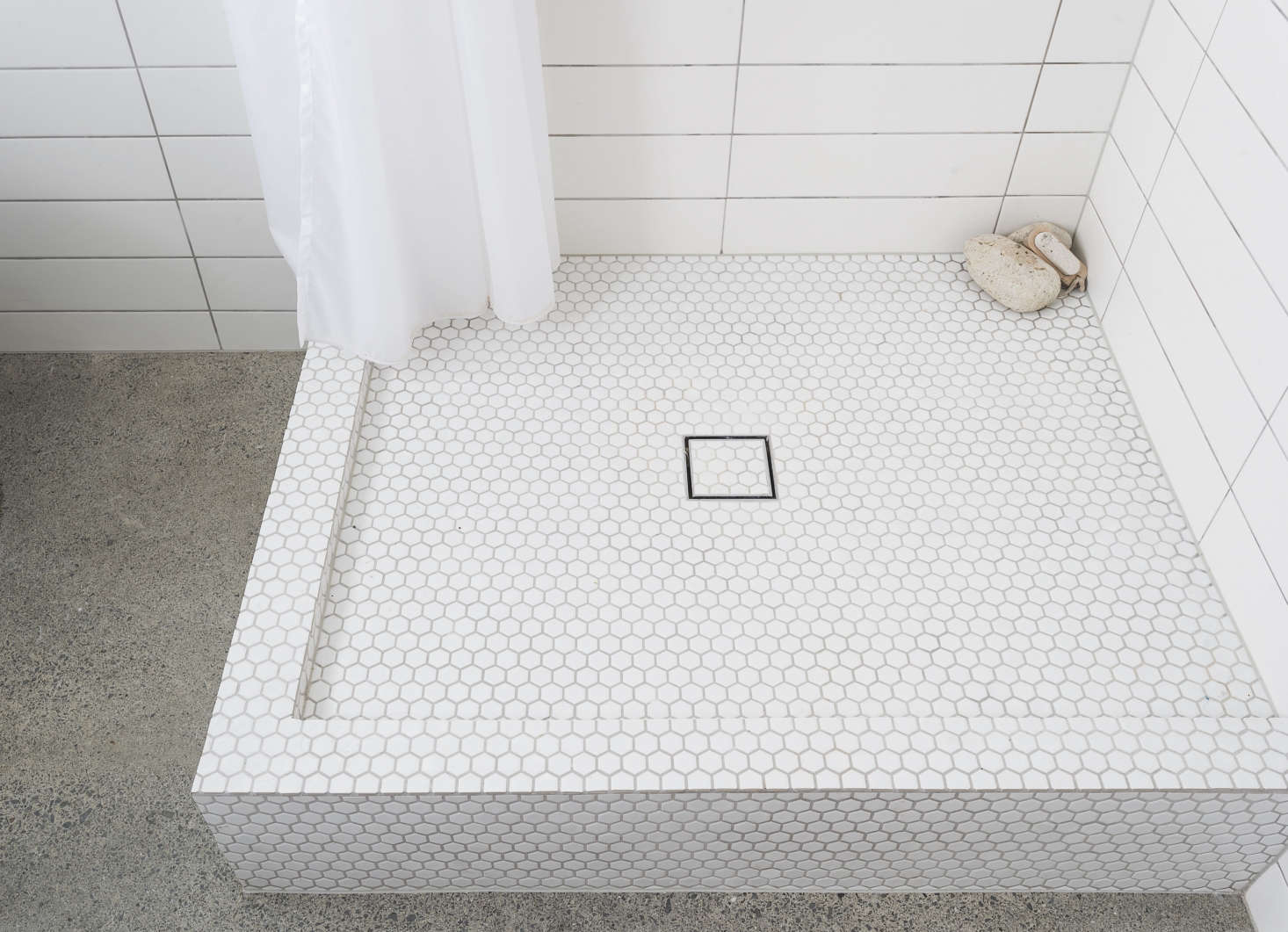 The new shower with sleek square drain; in the corner, a few pumice stones.