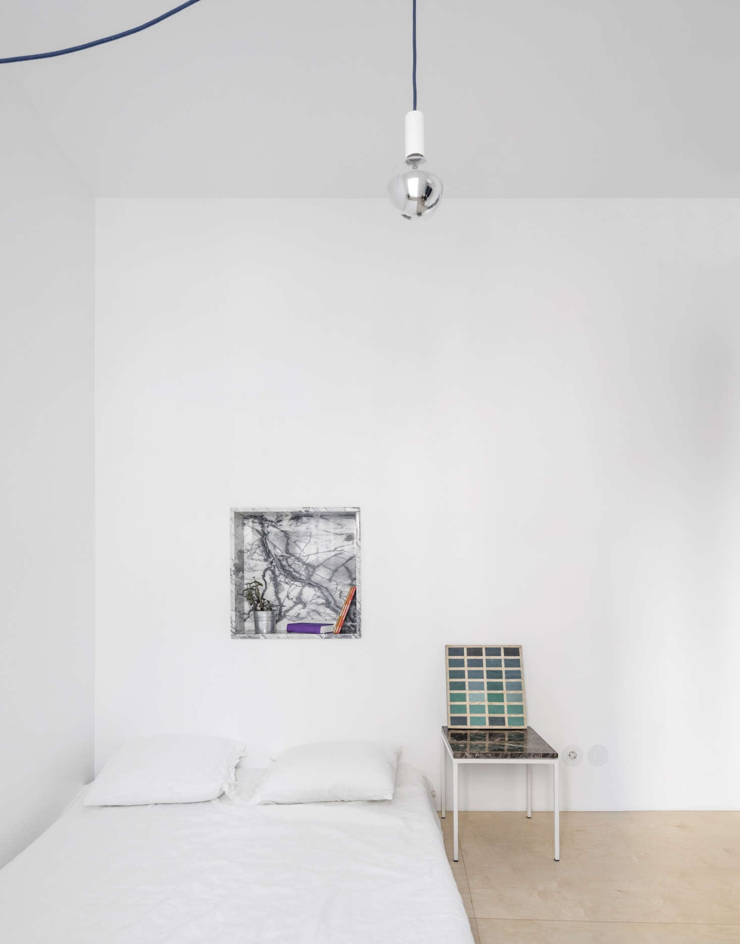 A marble niche and bedside table in a Lisbon apartment designed down to the furnishings by architectural collective Fala Atelier. We featured the project in A Narrow but Glamorous Marble-Clad Apartment. Photography by Fernando Guerra, courtesy of Fala Atelier.