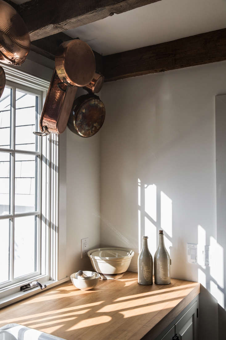 in another corner of the kitchen, copper pans hang from iron wall hooks affixed 20