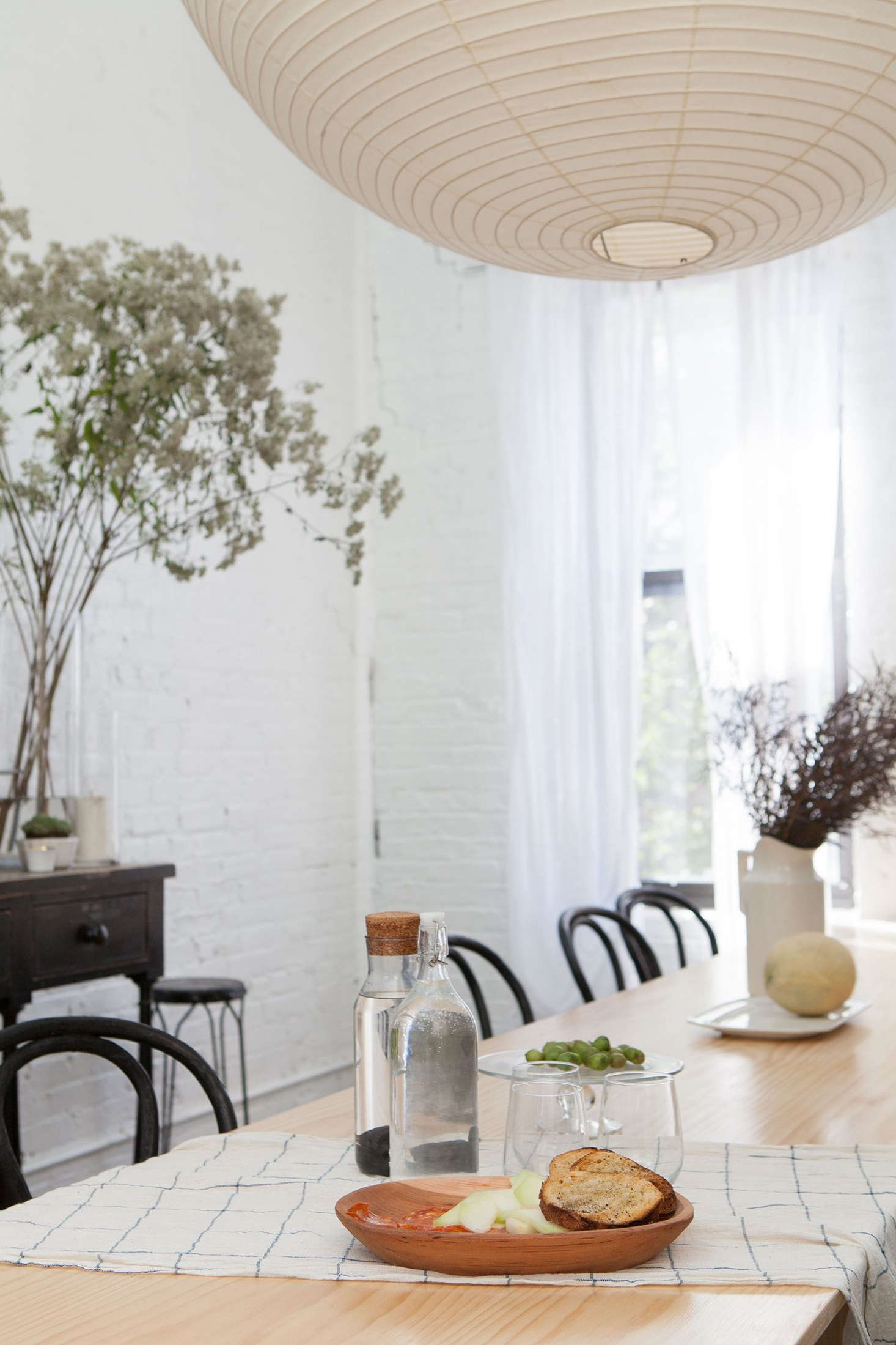 The dining area features a long, expandable table and black-painted bentwood chairs.