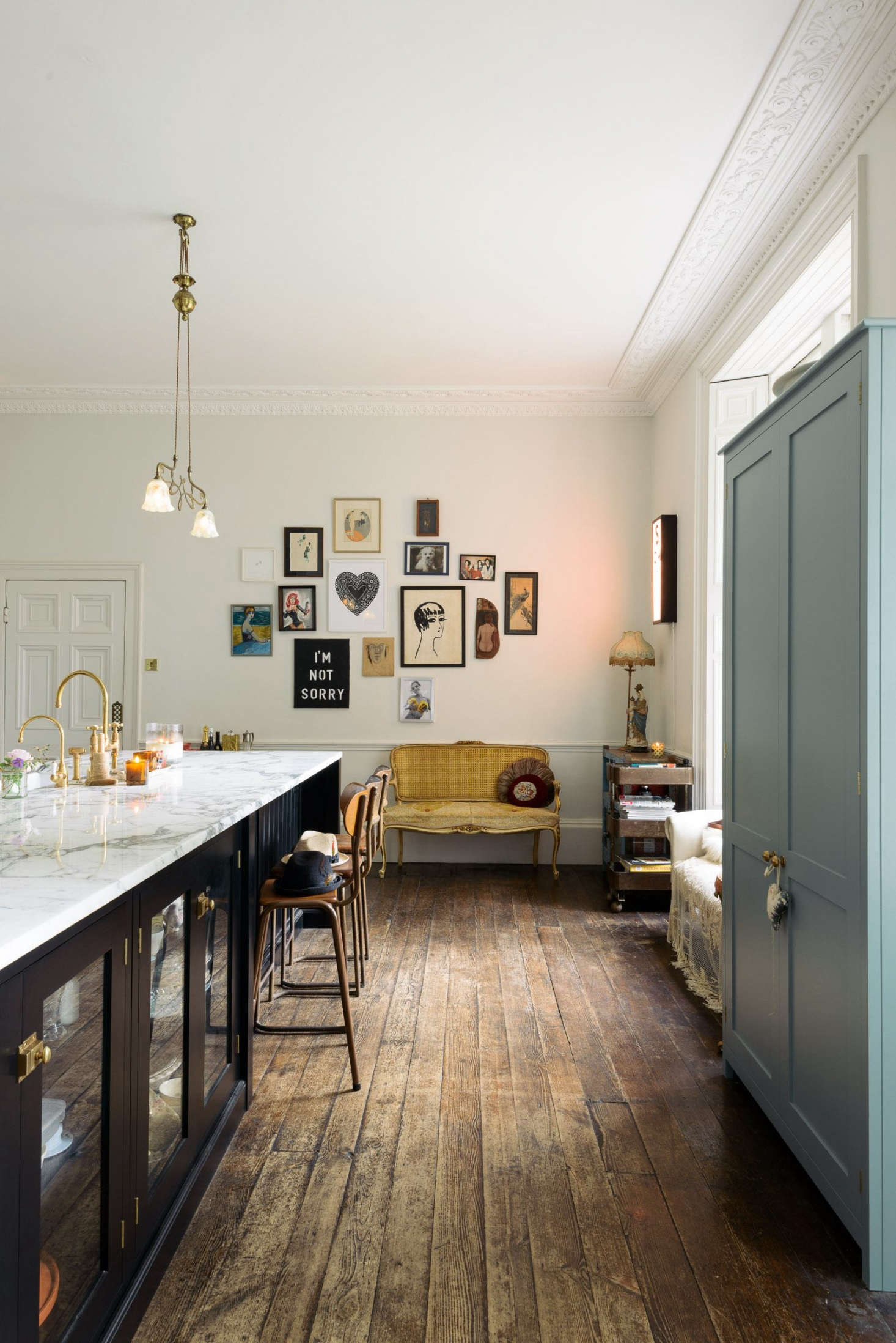 The faucet is a Brass Ionian Tap and Rinser by deVOL for Perrin & Rowe, paired with a hot water faucet. The art wall at the back of the kitchen mixes flea market finds with pieces by Zoe Grace, a contemporary artist and friend of Lowe