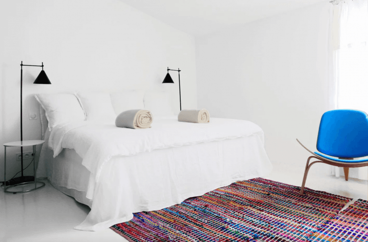 in the grande chambre, two multicolor rag rugs ground the otherwise all white b 29