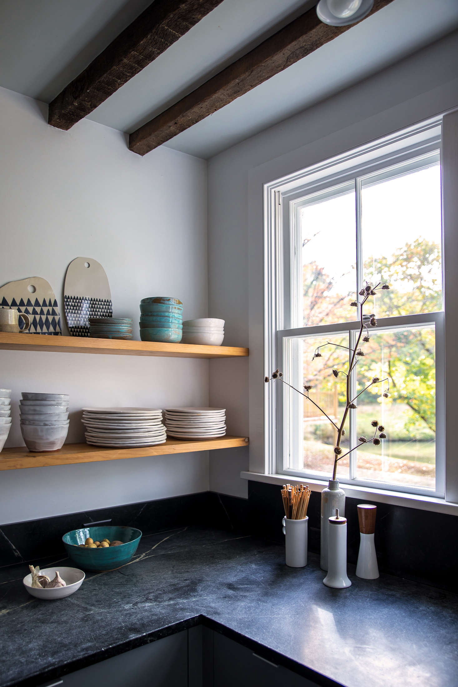To achieve a more open feel and introduce some warmer tones, Dunja replaced overhead cabinets with open shelves made of pine.