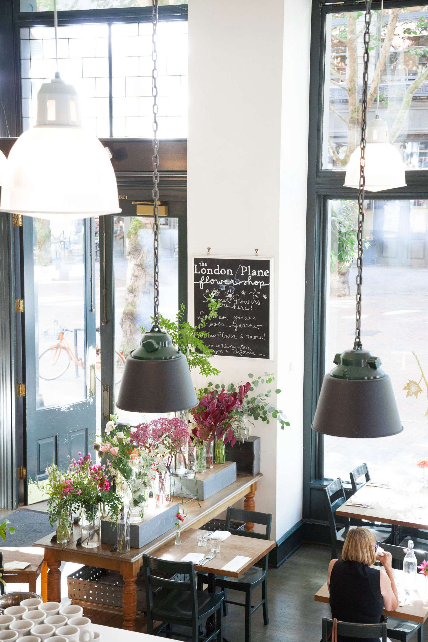 The entrance to the London Plane is flanked by a flower bar on one side and a pastry counter opposite.