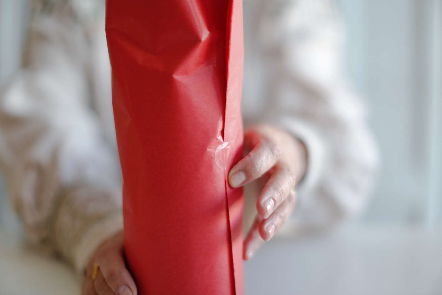 Step 4: Wrap the tissue paper around the bottle, leaving the glass bottom exposed. Fold back the free edge and secure with tape or glue (see note below). Next, wrap the scalloped jacket around the bottle, fold back the free edge, and again secure with tape or glue.