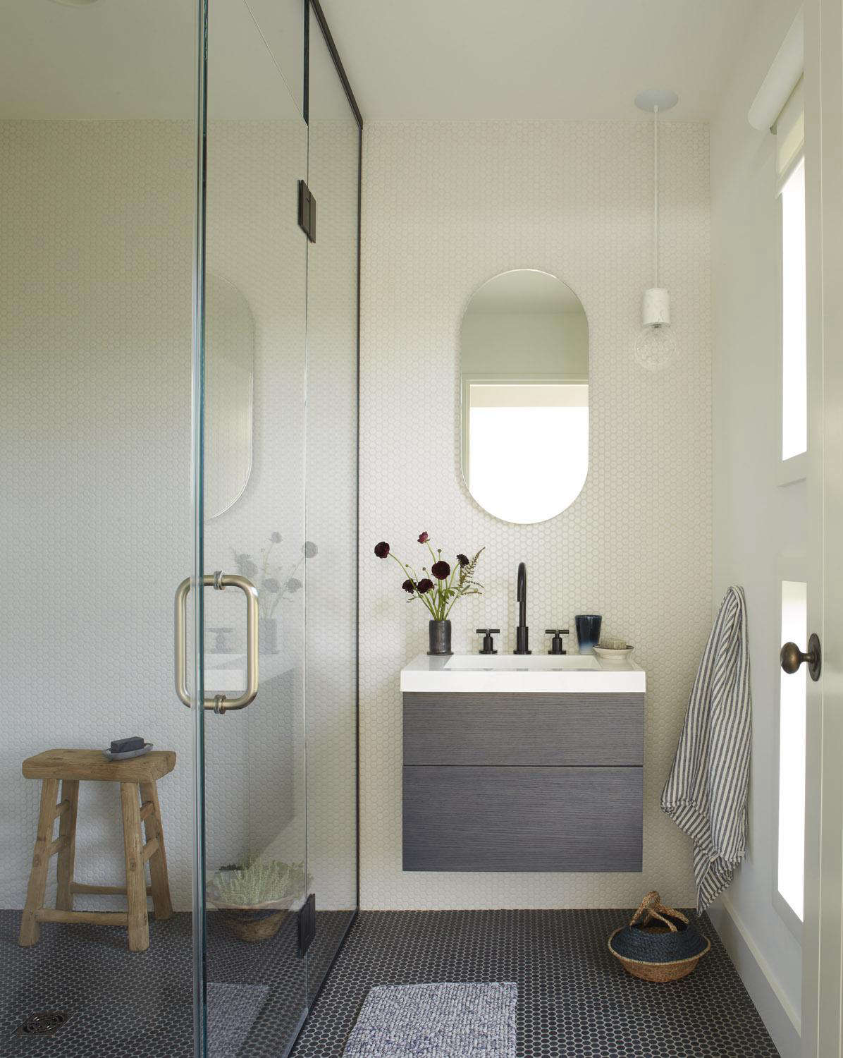 A small bathroom with shower serves the upstairs social spaces (the living room and kitchen). The wall-mounted vanity is from WetStyle and the wall and floor tile is Ann Sacks.