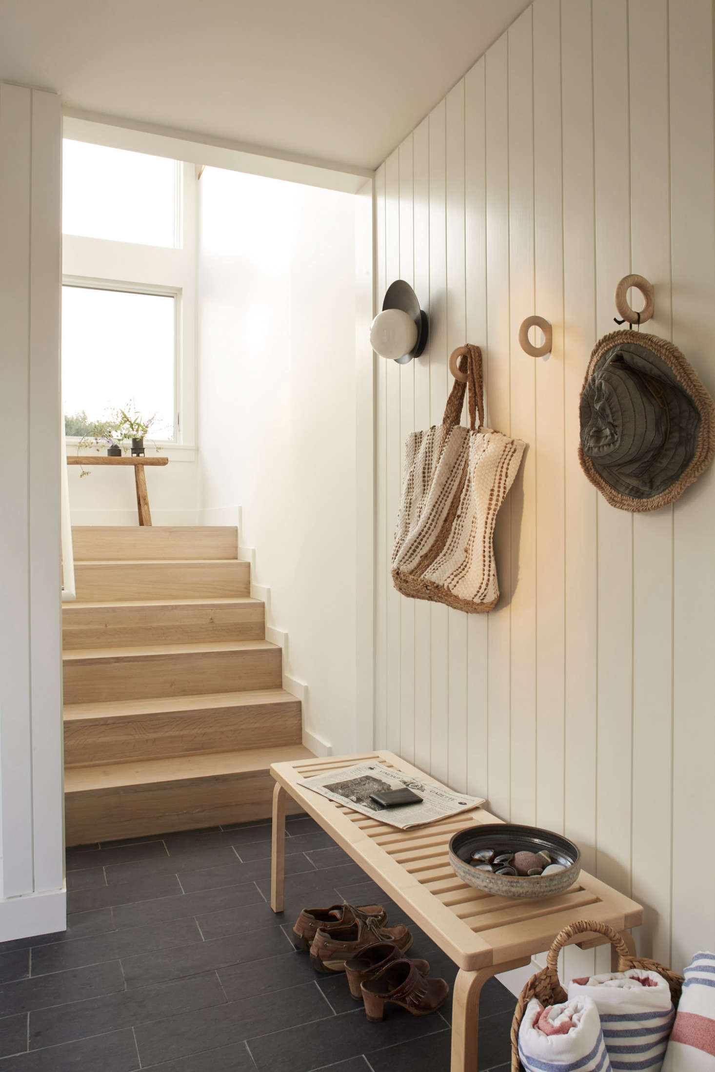 A small, slate-tiled entryway vestibule has hooks for storage and a bench for tying shoes (see our story on The Organized Home today to re-create the look).