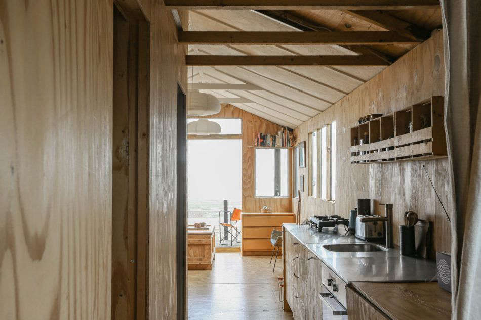 The view from the back of the house, through the kitchen, and onto the deck. Photograph by Marcia Mihotich from Two London Creatives Shore Up a Tiny Beach House, Ikea Hack Kitchen Included.