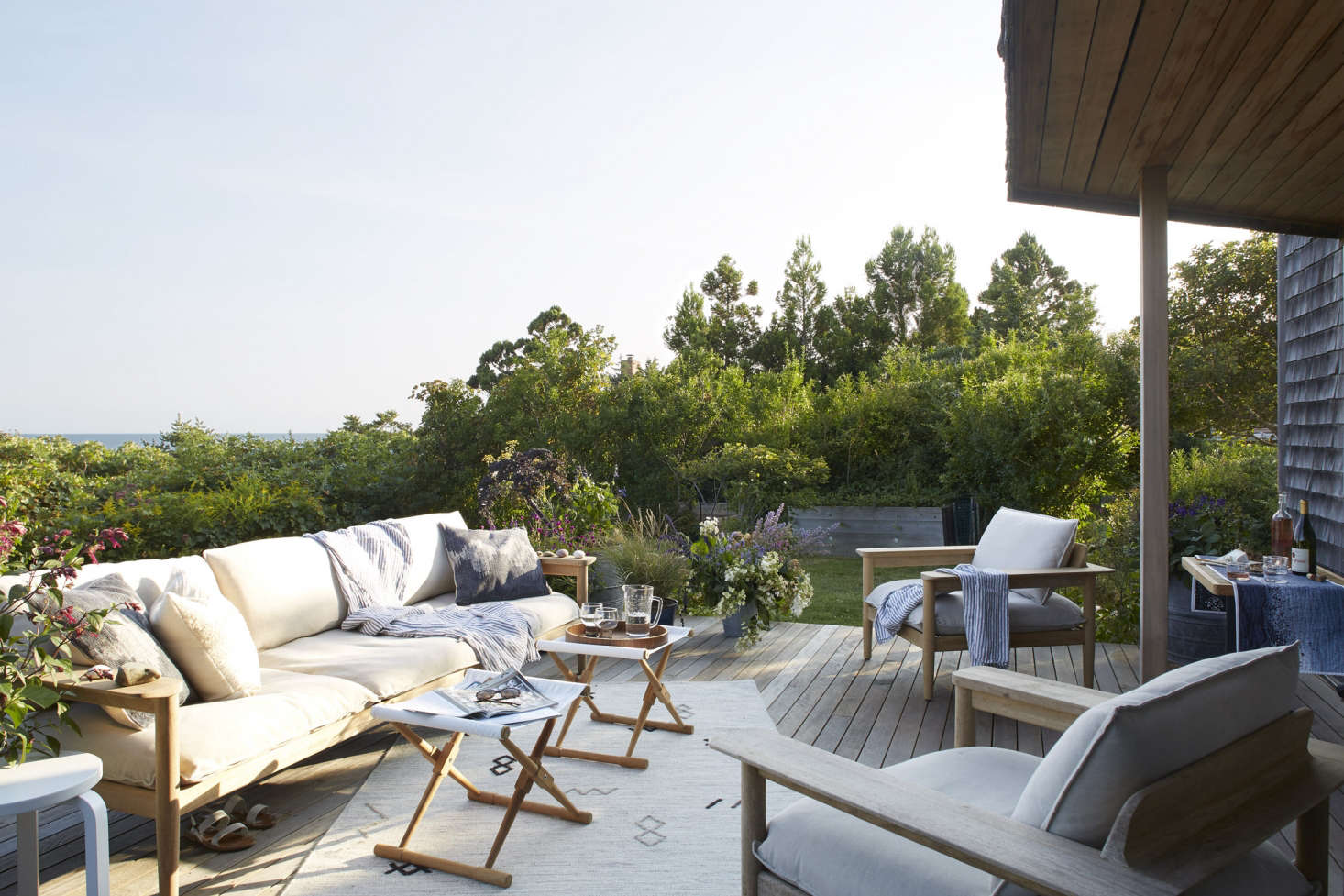 A large deck is accessed via sliding glass doors off the bedroom. The Terassi sofa and side chairs are from DWR. The canvas Camp Stools are from Serena & Lily.