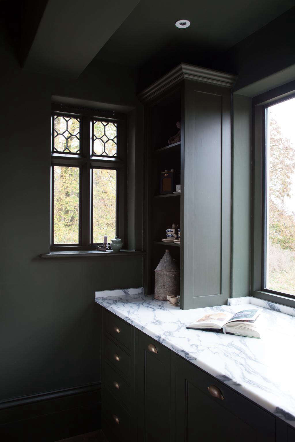 A stretch of countertop to the left of the sink is serene, thanks to a few tricks at work: Beneath the counter is (from left) a set of drawers, a cupboard for the trash bin, and the hidden dishwasher; the open shelving above is fitted with outlets for plugging in lighting and the owner