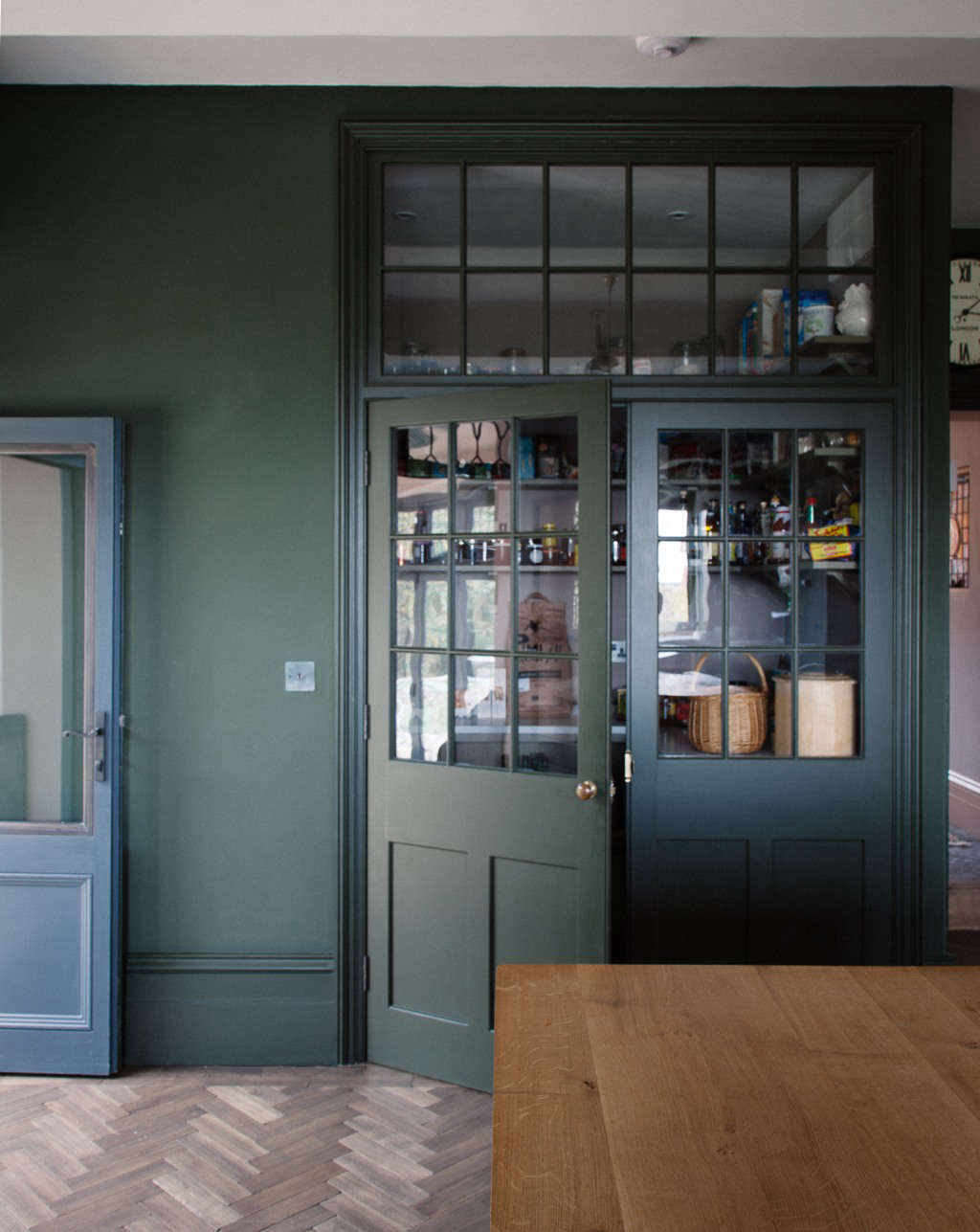 Another feature that keeps the kitchen clutter-free, without installing heavy upper cabinets: a generous built-in larder. Plain English designed two doors—one fixed, one hinged—to add more usable space within the larder (since they could add shelving and a honed Carrara marble counter along the fixed door) and painted it in Drab SCdata-src=