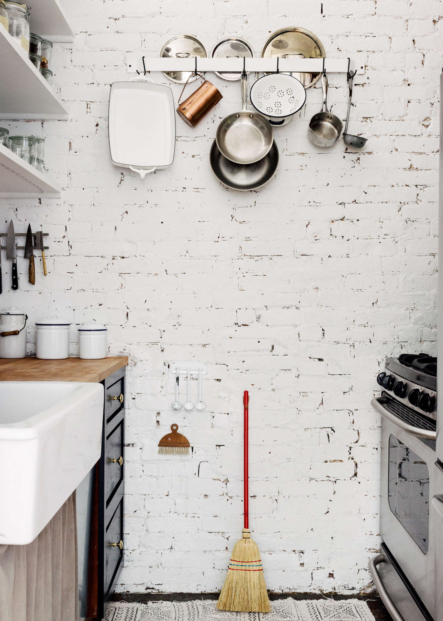 A red-handled broom provides a point of contrast to the white brick wall in Picture Room owner Sandeep Salter